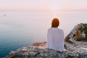 Woman sitting on a rock watching the ocean