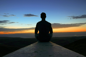Man Meditating on a Rock by a Sunset