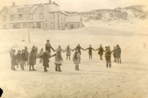 a woman and group of children outside in the snow