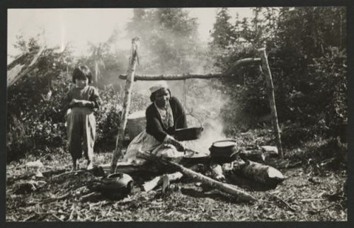 innu woman cooking meal over campfire