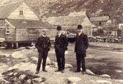 Three men standing near sheds