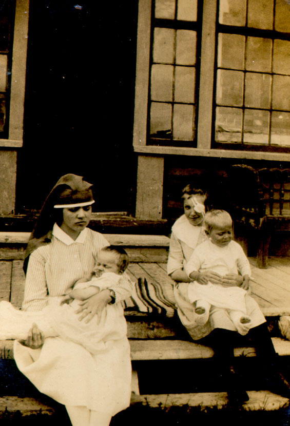 A nurse and three injured children sitting on the front steps of the St. Anthony hospital
