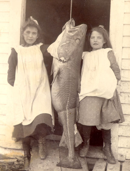 Two young girls with a large codfish.