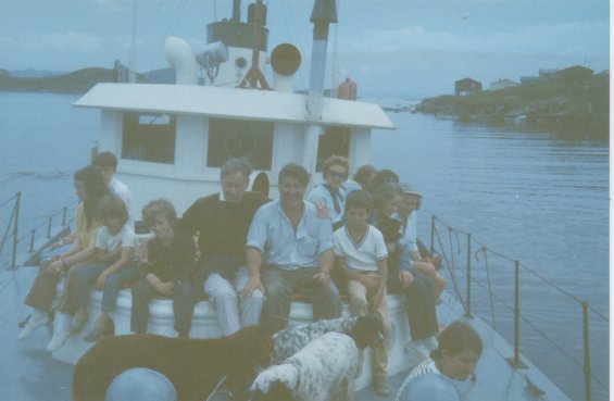 Harold L. Lake (centre) with a group of people and their dogs on a boat