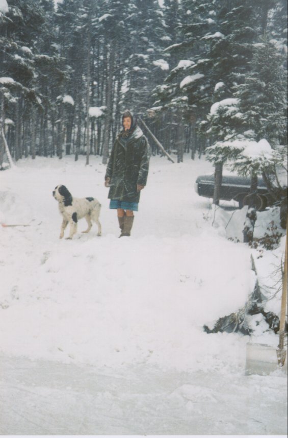 Unidentified woman standing in the snow with a dog