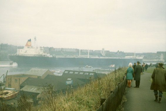 People looking at a large ship in a harbour