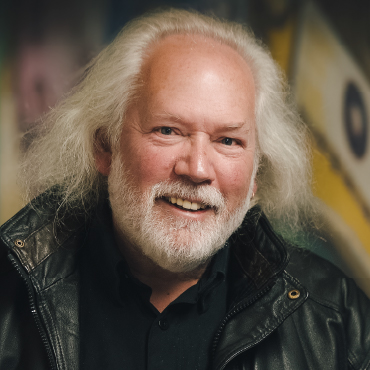 A head shot of Tom Gordon. He’s wearing a black leather jacket and a black collared shirt.