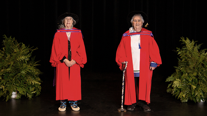 A photo of Elder G. Jean Crane and Elder Nellie May Winters in academic robes on stage at a special convocation ceremony held in Happy Valley-Goose Bay.