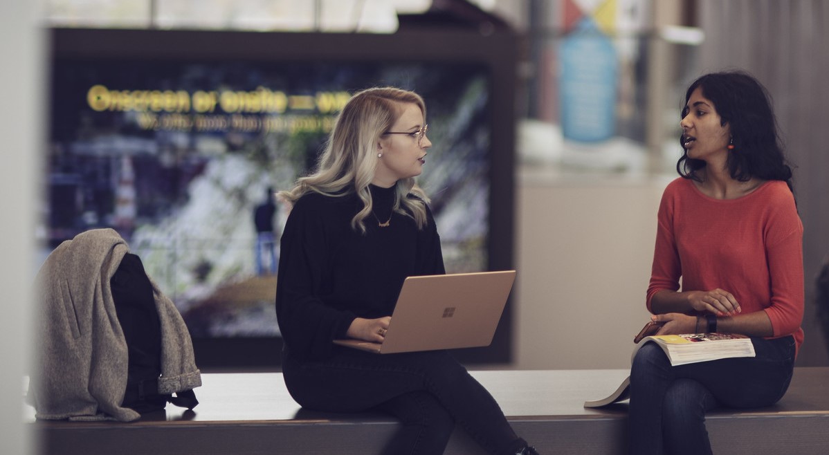 Two people sitting, facing one another having a conversation.