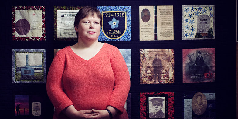 Tracy Madore in front of Peace-by-Piece: Quilted Memories of Newfoundland in the Great War