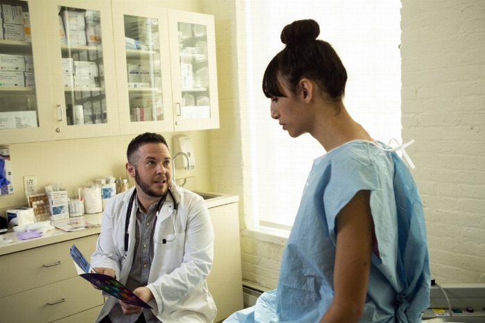 a transgender woman in a hospital gown speaking with a trans gender physician