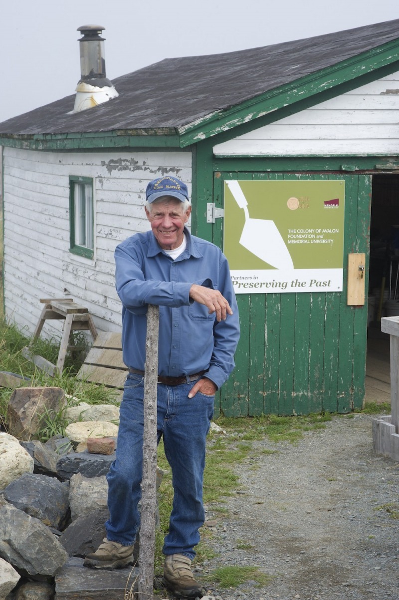 Dr. Jim Tuck in front of a shack in Ferryland, Newfoundland