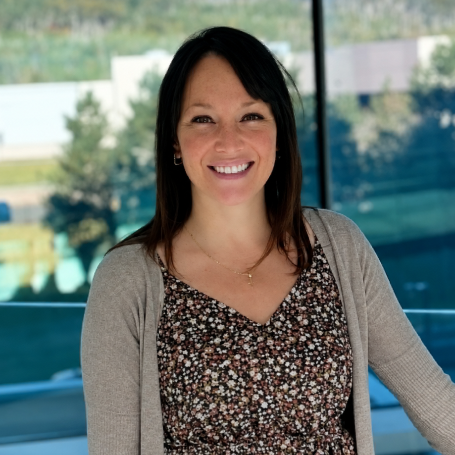 Staff member smiling into the camera in front of a large pane of glass