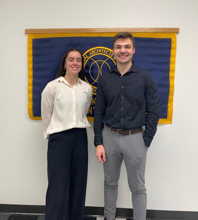 Paige Bodnar and Zack Greenham, SNAME scholarship winners, smiling in front of a blue and gold banner.