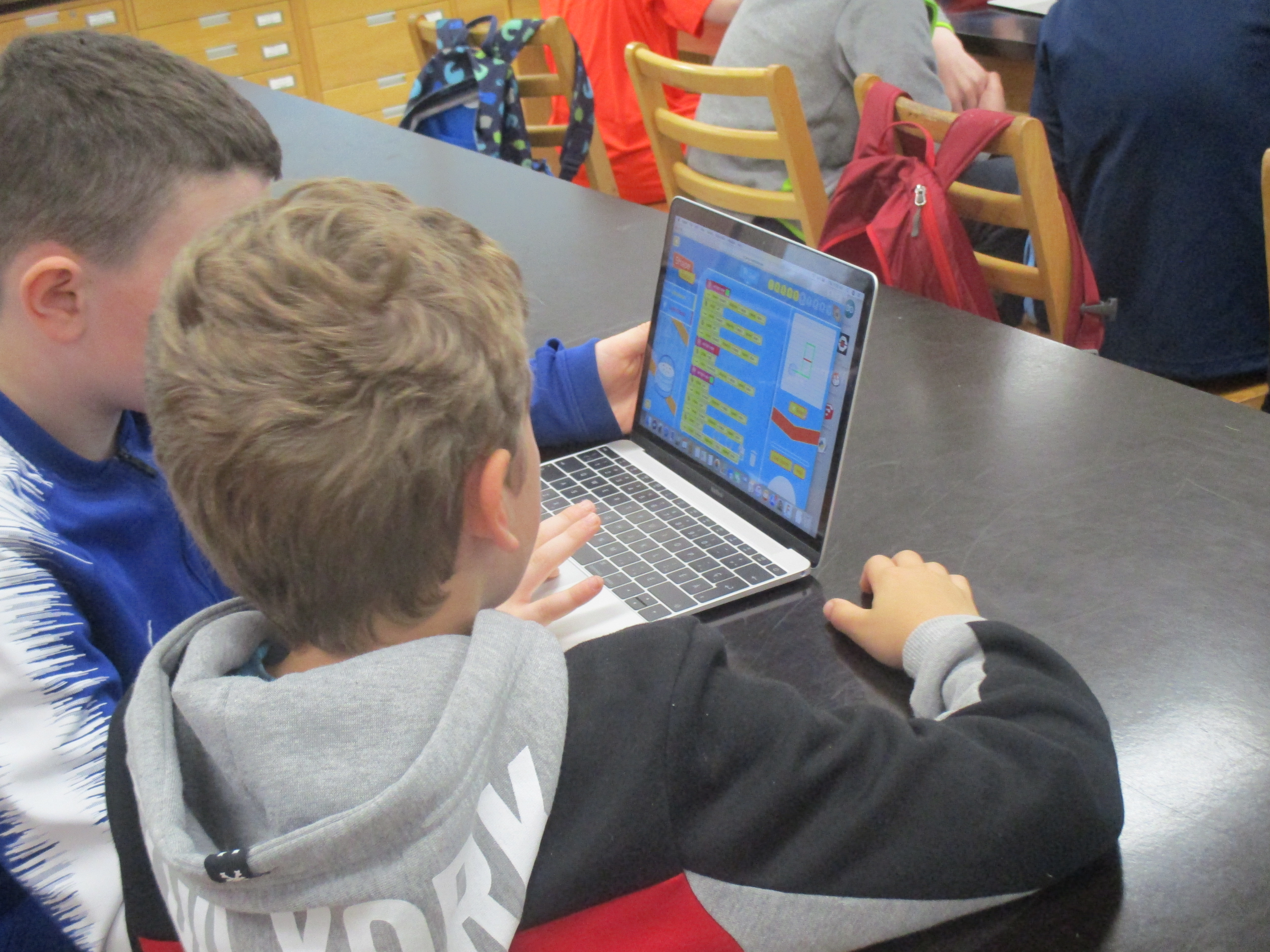 two boys using educational software on a laptop
