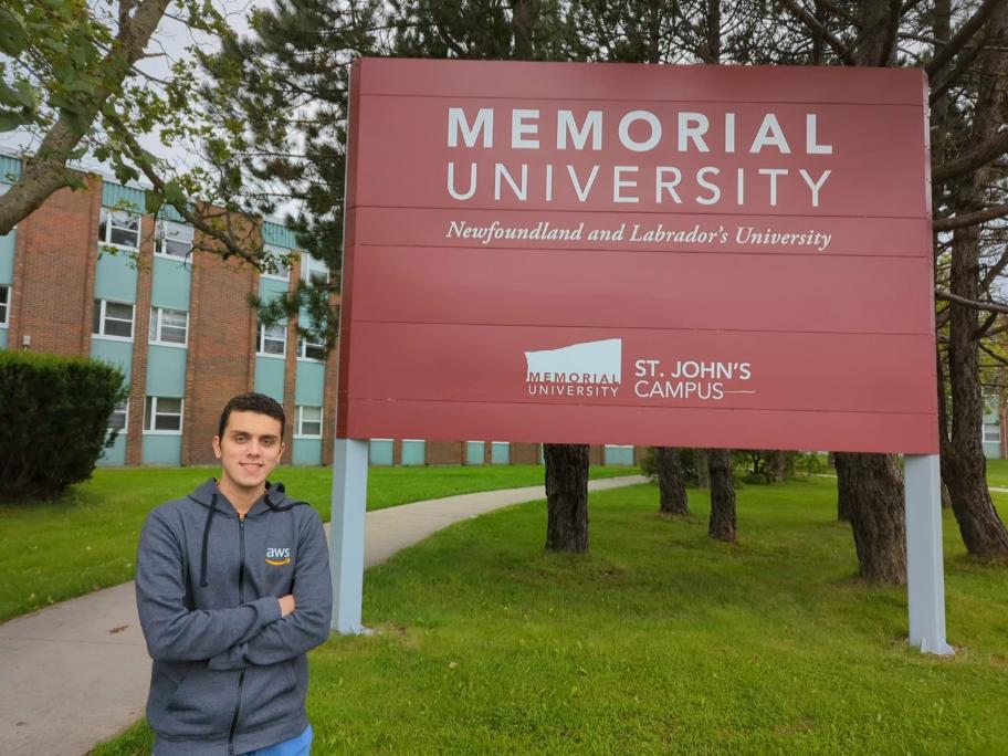 Man standing outside next to a Memorial University sign