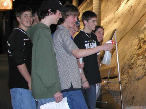 a group of five teenagers enjoying spraying water on the rock wall