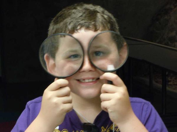 a young boy holds magnifying glasses in front of his eyes