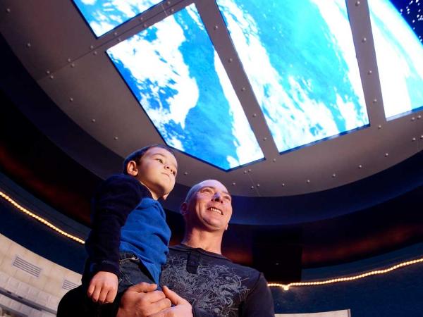 a father and young son look through a skylight to the heavens