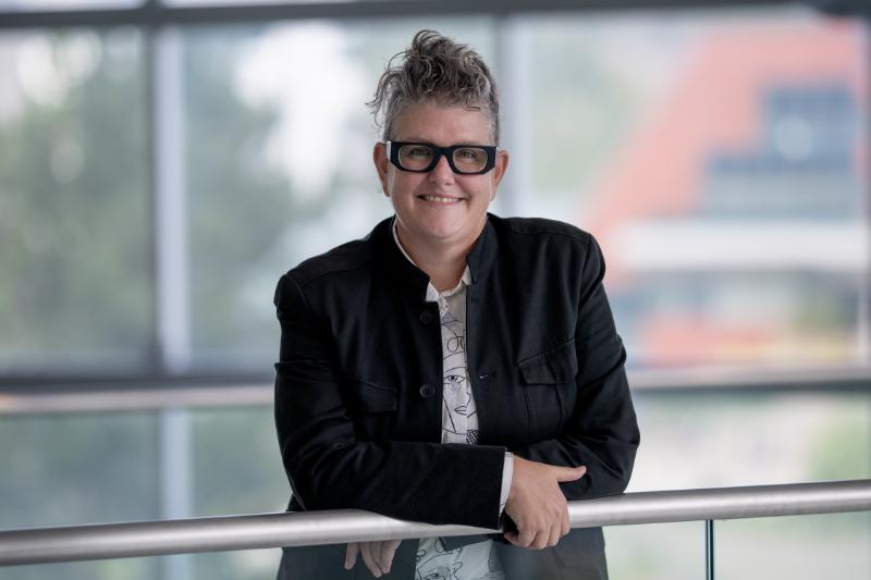 Dr. Natasha Hurley leaning on a metal rail with windows in background