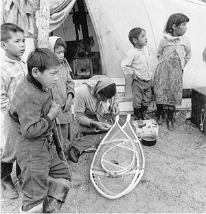 Innu woman making snowshoes in front of her tent at Utshimassit (Old Davis Inlet), early 1960s. Credit: Ray Webber