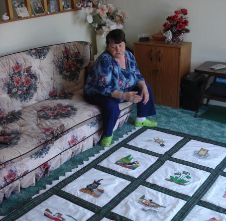Coombs, Inga. Inga Coombs with one of her painted Newfoundland quilts, Main Brook. 