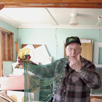 Elliott, George. George Elliott holds a model castnet, Main Brook