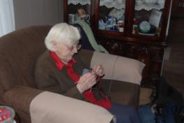 Simmonds, Mary Jane. Mary Jane Simmonds knits in her living room, Conche, Newfoundland