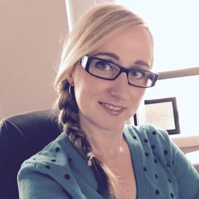 Picture of April, a smiling woman with glasses and a blonde braid and green sweater