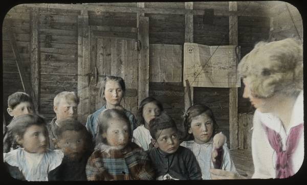 Woman (visitor?) with children in school, 1915