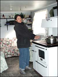 Evie Plaice warming her hands over the wood stove in Triangle, Labrador