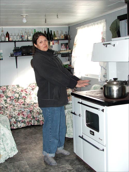 Evie Plaice warming her hands over the wood stove in Triangle,