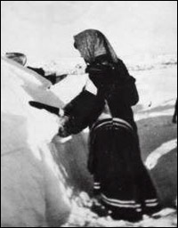 A woman shaping a snow igloo