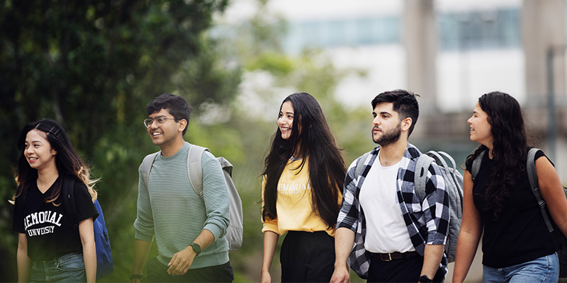 Five students with backpacks walking outside
