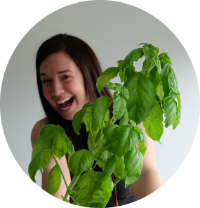 Emily Bland holding growing basil plant.