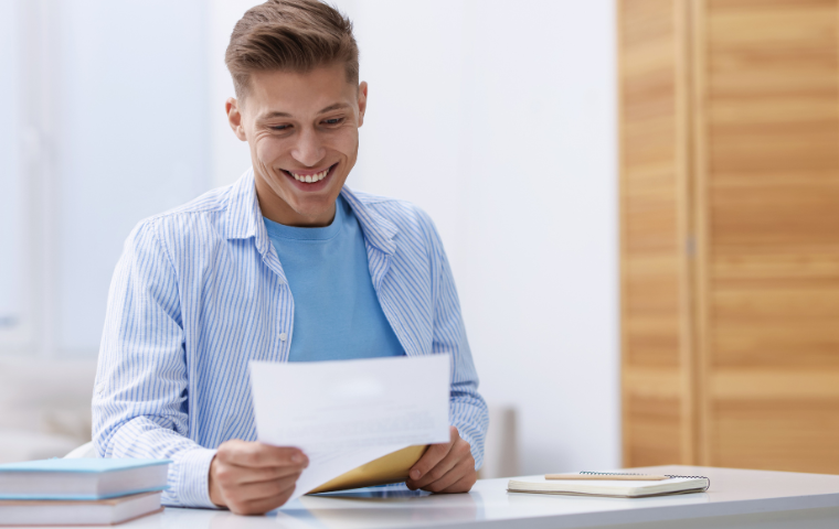A student reading an acceptance letter and smiling