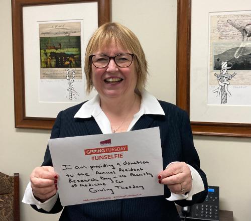 A photograph of Dr. Margaret Steele holding up a piece of paper reading 'I am providing a donation to the Annual Resident Research Day in the Faculty of Medicine.'