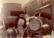 A cooper standing with Job Brothers & Co. herring barrels