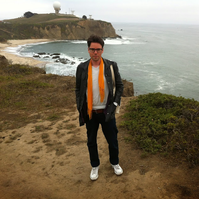 A man stands on a cliff overlooking the ocean