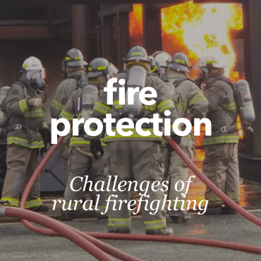 Picture of a group of fireman holding a hose to dampen a fire.