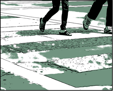 Two sets of legs cross a cross walk on a paved street.