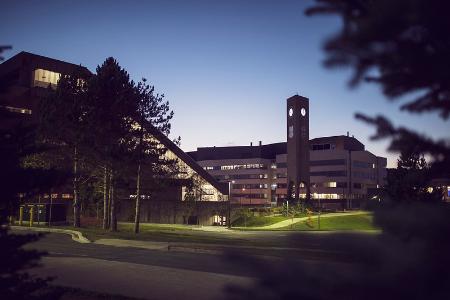 A landscape image at dusk with the library and university clock tower in the foreground and the core science facility in the background.