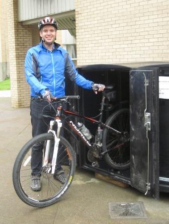 Individual parking a bike in a bike locker on St. John's campus